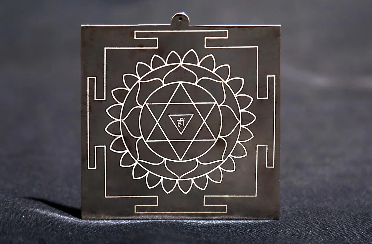 Silver yantra engraved in the family tradition, a geometric mandala with a bija mantra at its centre